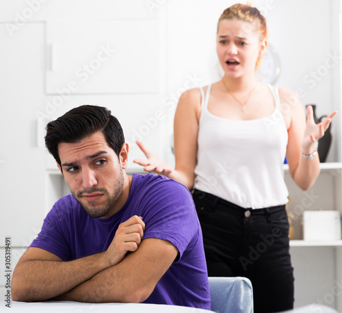 Upset man at table with disgruntled woman behind