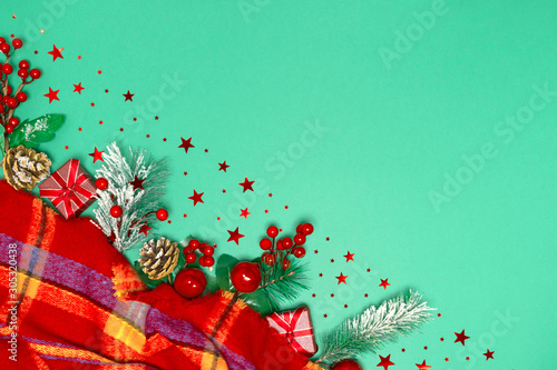 Gifts, berry fir branch, snow cones under scarf on green backdrop from above. 2020 New year composition. Stylish decor concept, Flat lay, copy space. For postcard, for desktop, for blog, advertising