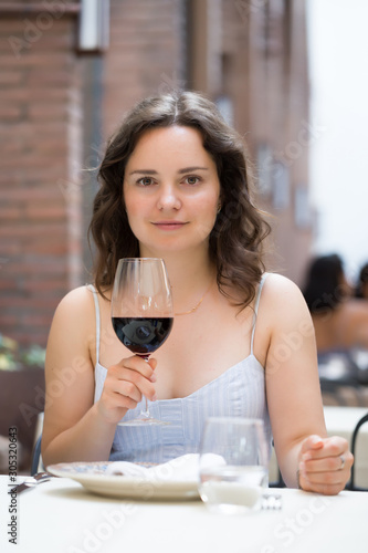 Woman with glass of red wine sitting at outdoor restaurant photo