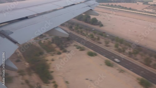 Aerial view out of an Etihad Airways Airbus A320-200s right window on final approach on Abu Dhabi international airport passing a desert highway while sunset. photo