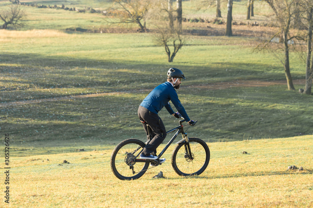 Cyclist in pants and fleece jacket on a modern carbon hardtail bike with an air suspension fork. The guy on the top of the hill rides a bike.