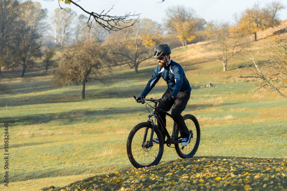 Naklejka premium Cyclist in pants and fleece jacket on a modern carbon hardtail bike with an air suspension fork. The guy on the top of the hill rides a bike.