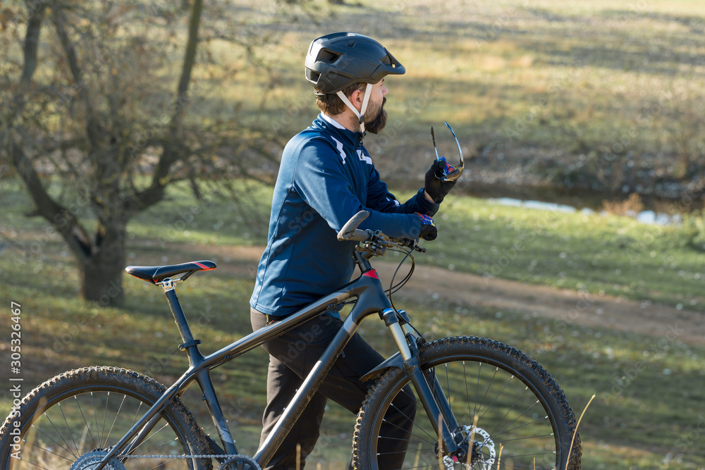 Obraz premium Cyclist in pants and fleece jacket on a modern carbon hardtail bike with an air suspension fork. The guy on the top of the hill rides a bike.