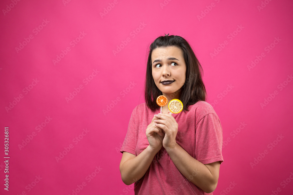 Portrait of lovely sweet beautiful cheerful woman with straight brown hair holding a lollipop near the eyes.