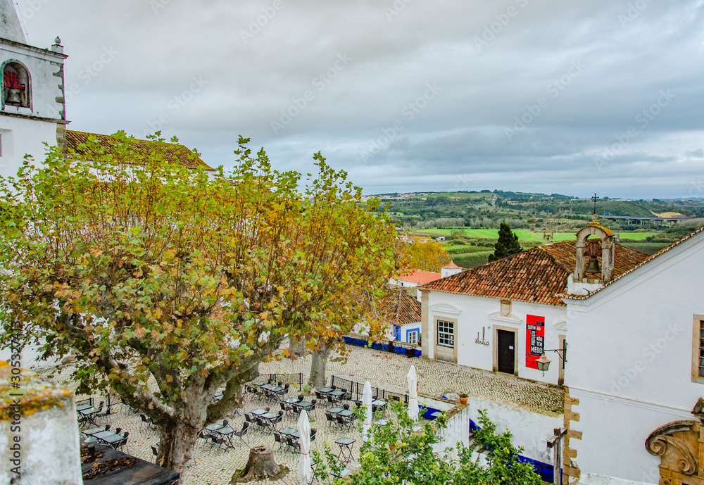 A top view of the town, Obidos in Portugal. Trees, houses, roofs, sky, clouds.