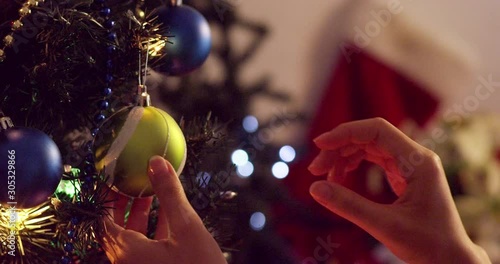 Hanging a green ball ornament on a Christmas tree with blinking lights - slow motion - shot on RED
