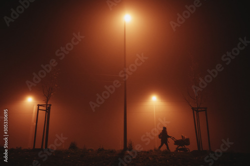 silhouette of mother pushing a stroller on a foggy evening