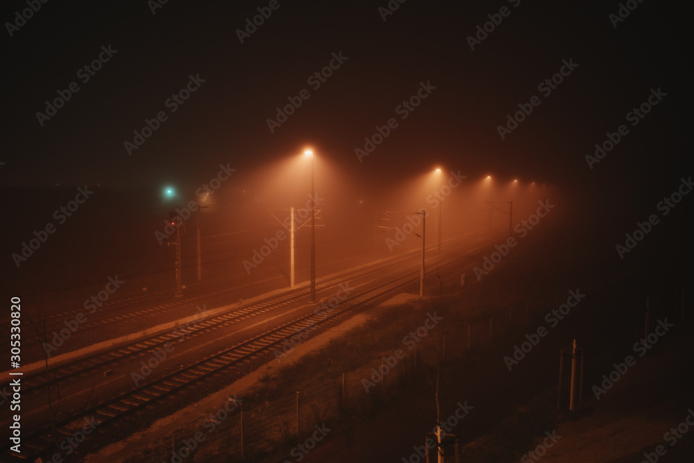 dramatic light surrounds railroad tracks on a foggy night in Leipzig, Germany