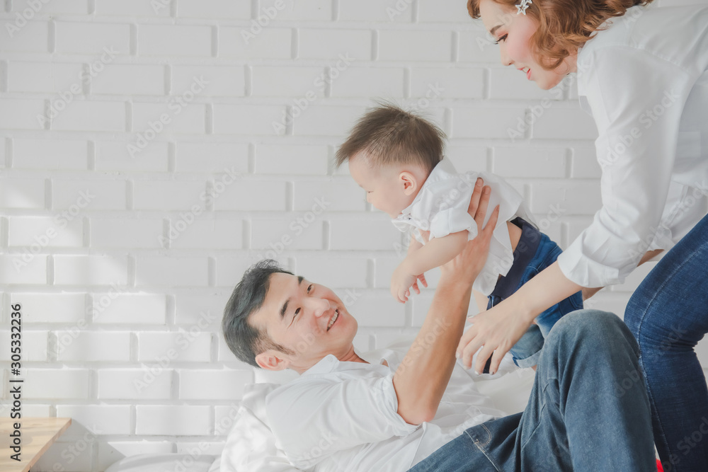 Fototapeta premium Asian Japanese Family father mother son wearing white shirt carrying child posing for photo on bedroom in white room.To keep memories moment cuteness of son in childhood