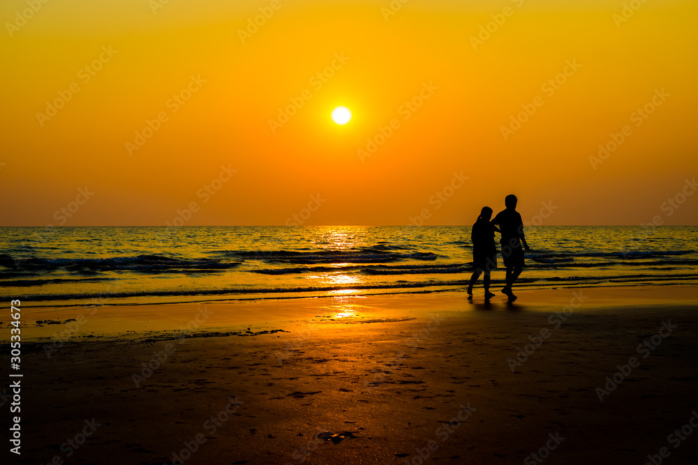 Siluate lovers and beach before sunset