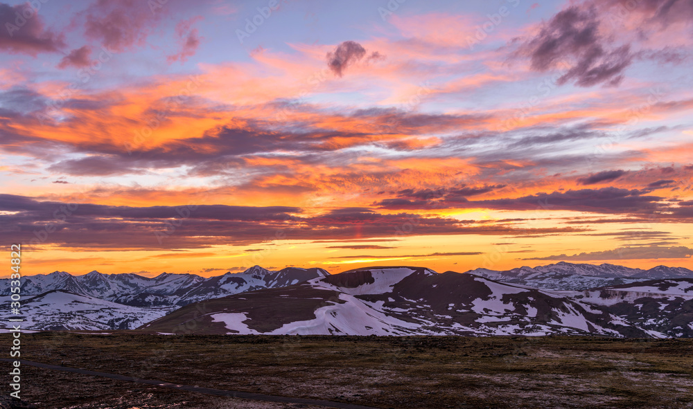 Sunset RMNP - A panoramic view of colorful Spring sunset sky over snow-capped high peaks of the Continental Divide at top of Rocky Mountain National Park, Colorado, USA.