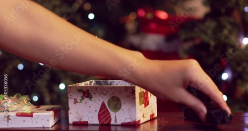 Woman placing coal into a gift box with Christmas tree in background - slow motion - shot on RED