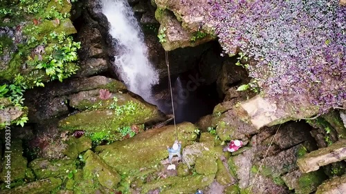 Men ready to drop into a hole with water cascading inside photo