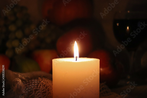Soft candle light home warmth autumn still life. Thanksgiving day with fruits and glass of red wine on dark background.