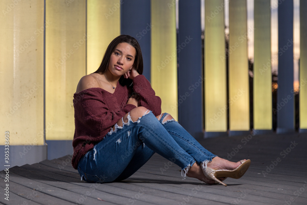 Full length of mixed raced teenage girl sitting infront of lit pillars ...