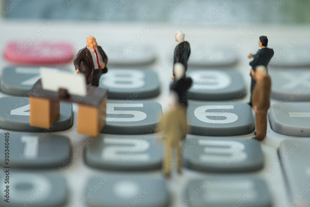 Miniature businessmen discussing on calculator about interest rates Miniature businessmen discussing on calculator about interest rates