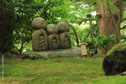 Small statues of baby buddhas surrounded by fresh green at the Hase-Dera temple in Kamakura, Japan photo