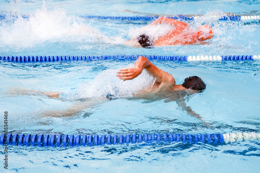 Motion blurred swimmers in a freestyle race, focus on water in foreground
