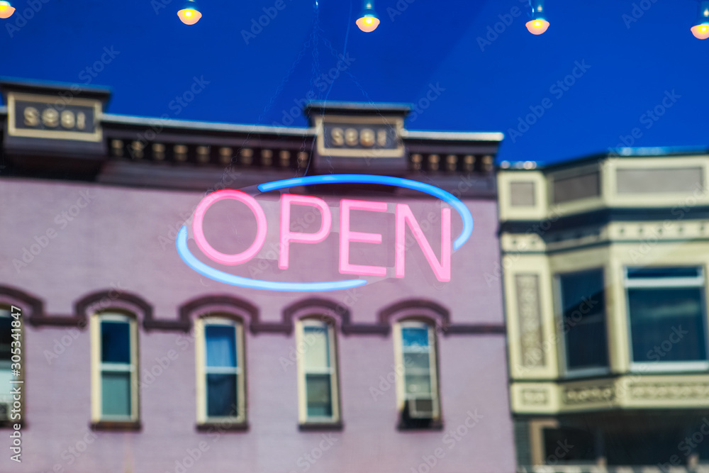 Neon Open sign in a business window with reflection of vintage buildings across the street Neon Open sign in a business window with reflection of vintage buildings across the street
