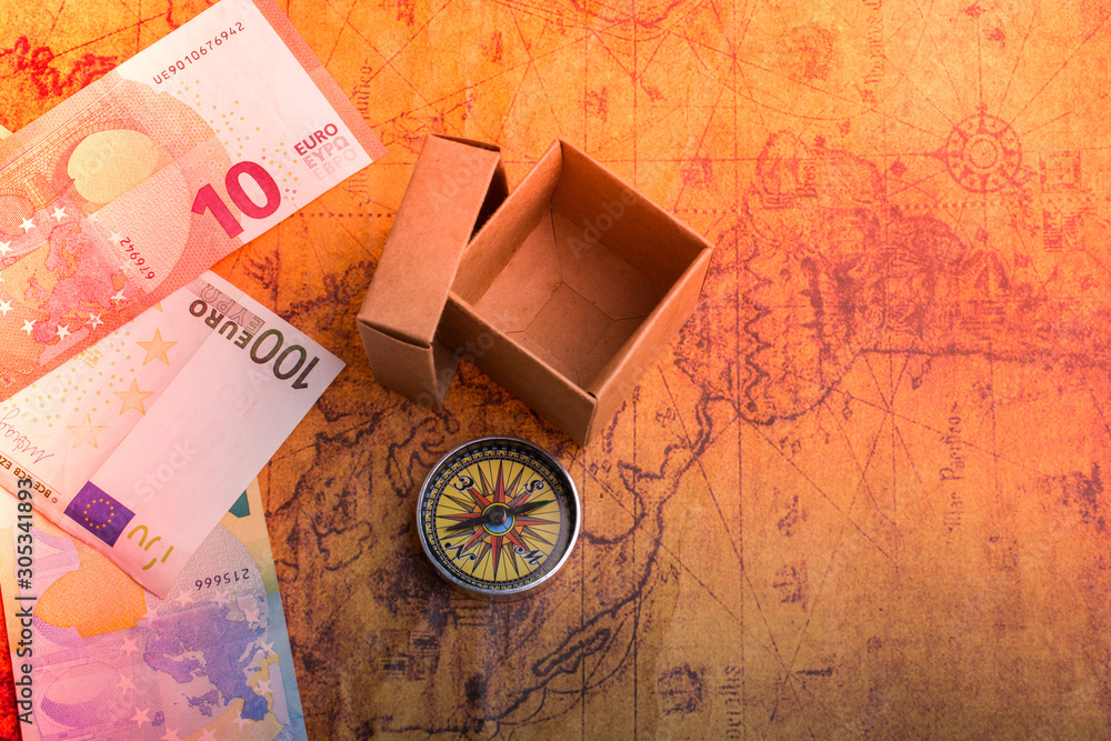 Compass beside a box and Euro banknotes  on an old map