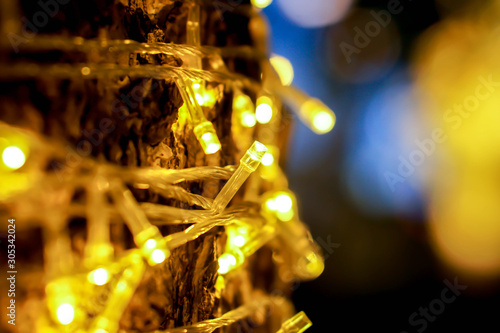 Closeup of Christmas lights and refection lighting on the tree with colorful blurred and bokeh and black background.