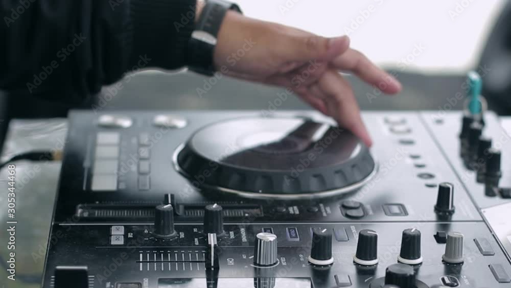 Close up shot DJ hand live perform; turn jog wheel move slidder fadder and switch the knob on dj mixer equipment controller; DJ daytime party Close up shot DJ hand live perform; turn jog wheel move slidder fadder and switch the knob on dj mixer equipment controller; DJ daytime party