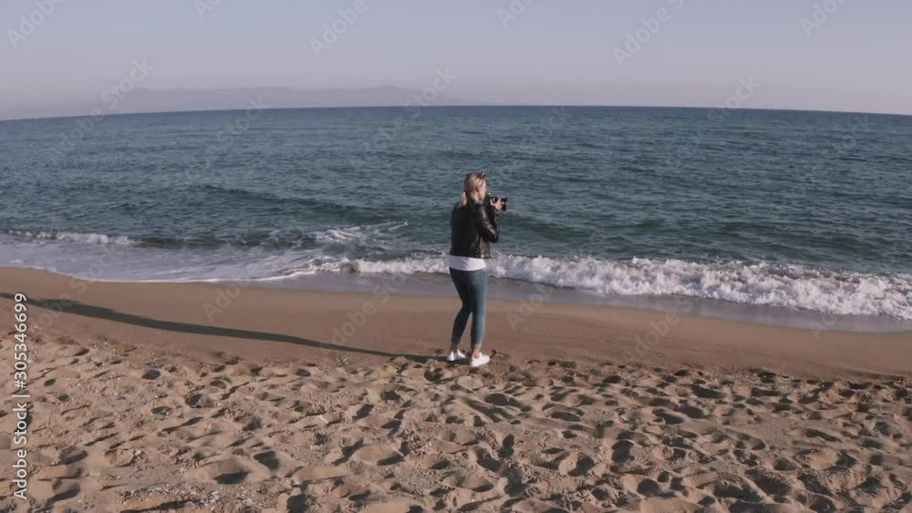 Woman photographer with DSLR camera taking pictures on empty beach during sunset. Woman photographer with DSLR camera taking pictures on empty beach during sunset.