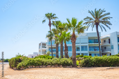 Cyprus. Protaras. Pernera. Hotels on the Mediterranean coast. Kalamies Beach. Palm trees and flowers on the background of the hotel. Beach holiday. Summer trip to Cyprus. © Grispb