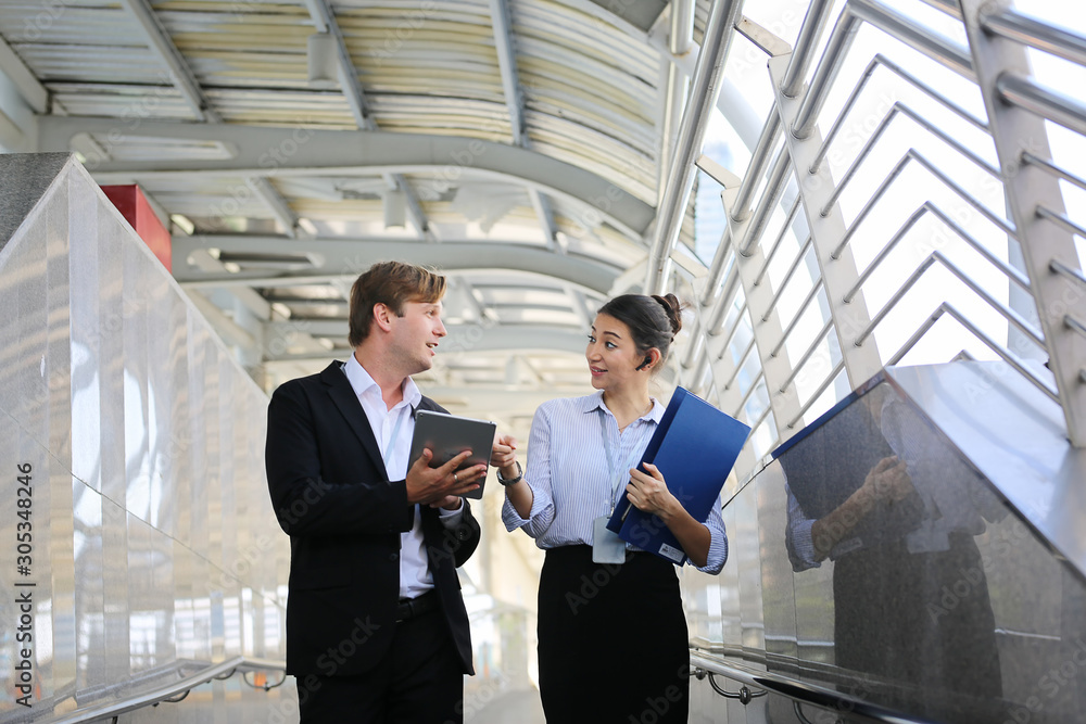 Concept of partnership in business. Young man and woman talking on business while walking on footbridge. Concept of partnership in business. Young man and woman talking on business while walking on footbridge.