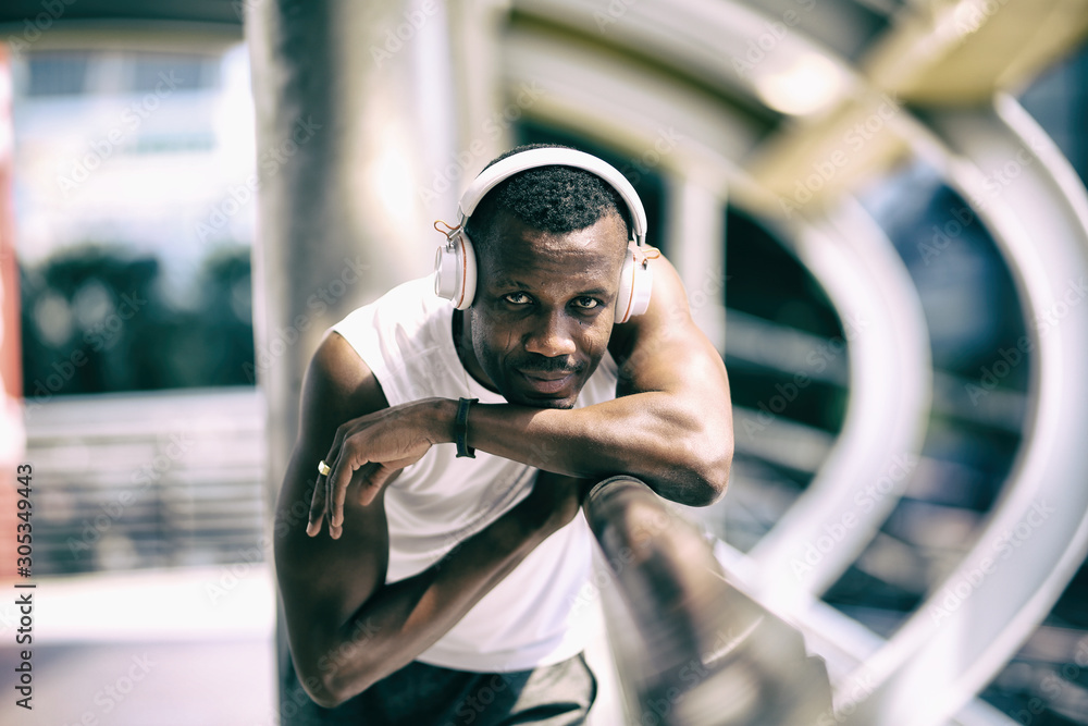 Head shot of Sportsman African american with headphone listening music outside on street Head shot of Sportsman African american with headphone listening music outside on street