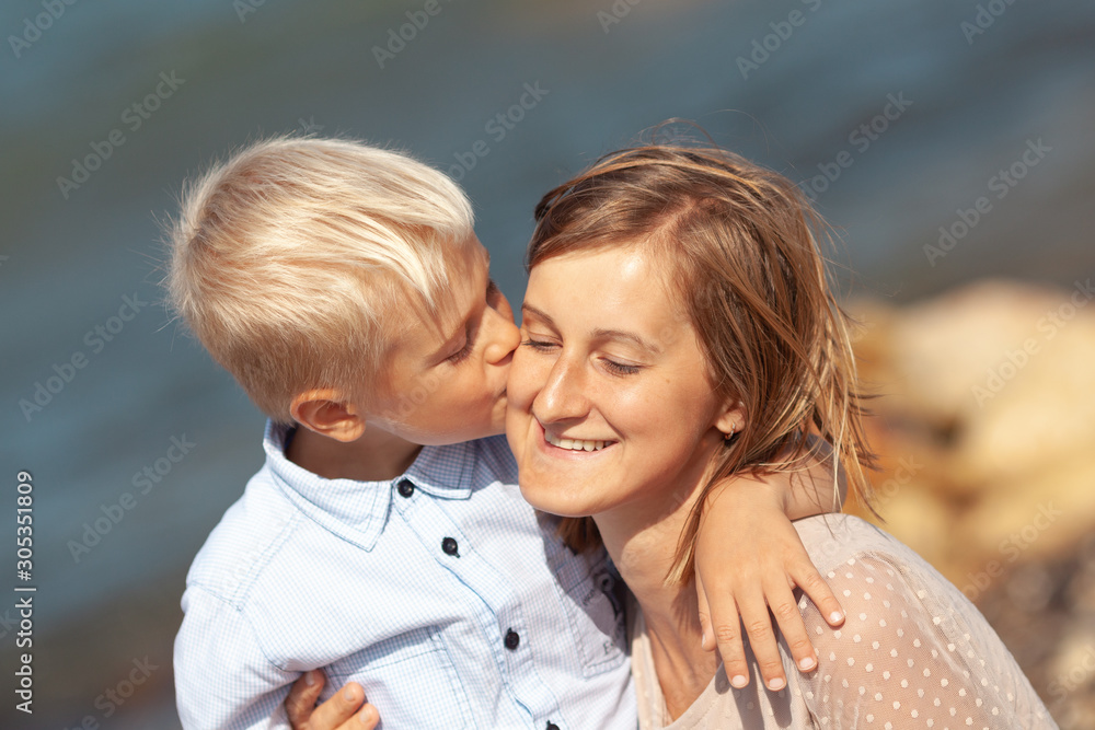 Fototapeta premium Portrait of happy beautiful mom and son on sea background