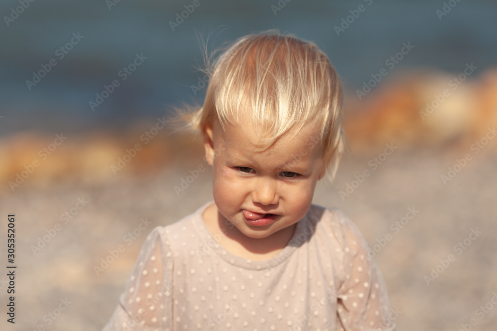 Portrait of a pretty little girl on the background of the sea, the baby walks on the shore Portrait of a pretty little girl on the background of the sea, the baby walks on the shore