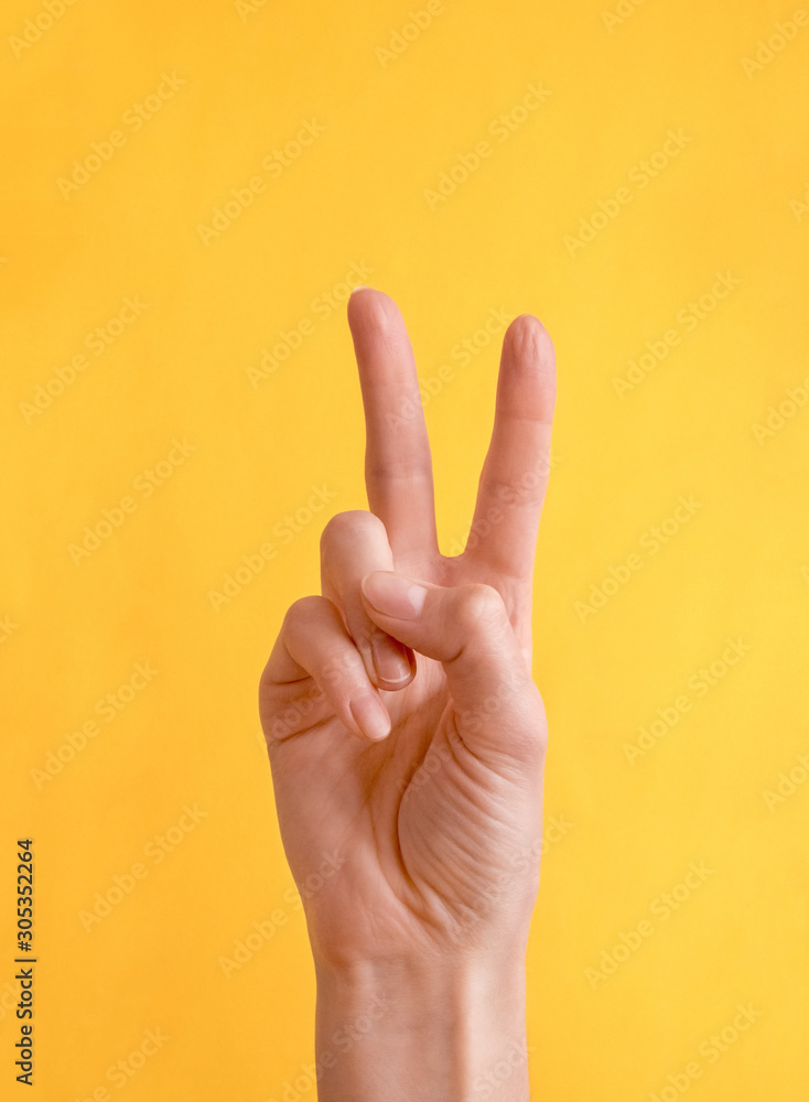 Young woman showing peace or victory gesture on color background Young woman showing peace or victory gesture on color background