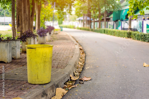An old yellow dustbin in the public park beside the walk way for protect environment.