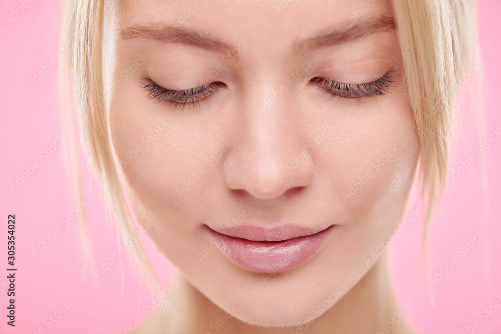 Face of young blond serene woman with natural makeup looking down Face of young blond serene woman with natural makeup looking down