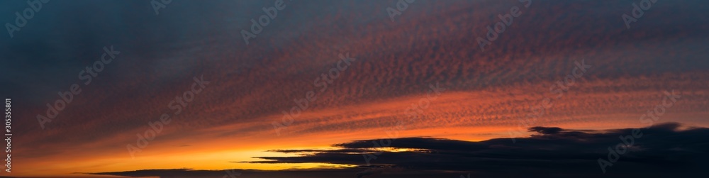 Fototapeta premium Fantastic dark thunderclouds at sunrise, wide panorama