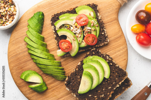 Rye bread toast with avocado, tomato, sprouts. Healthy food, vegan vegetarian snack, weight loss concept. Table top view