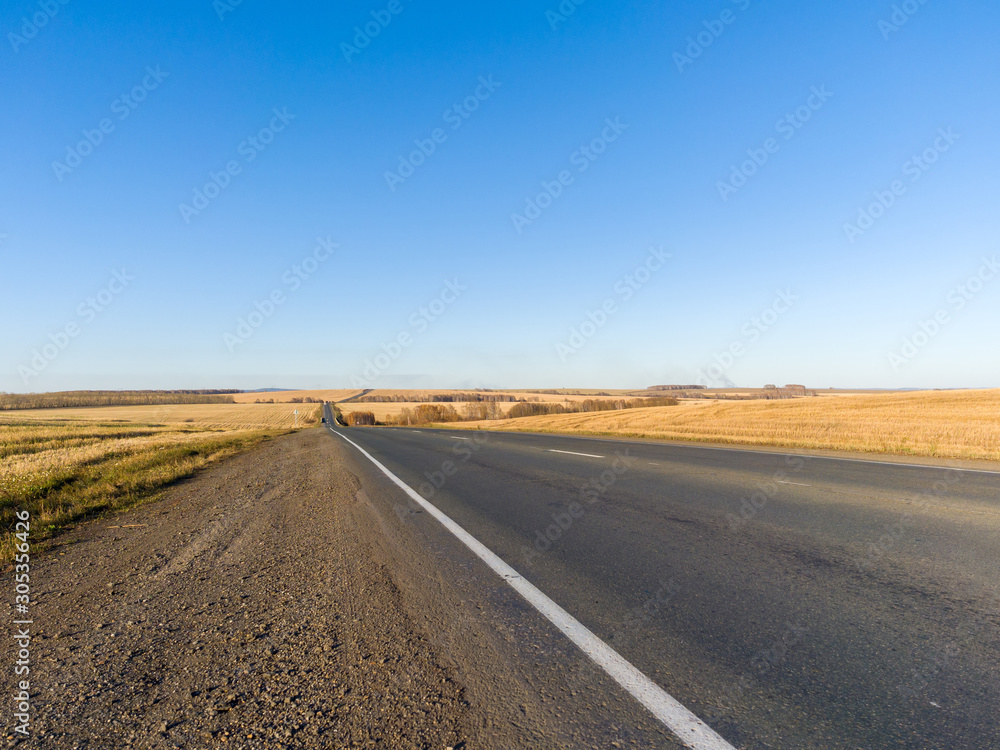 The highway goes into the distance. Rural landscape sunny autumn day