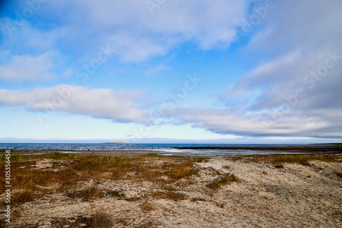 Norway landscape with beach of the Northern sea in sun day with white clouds