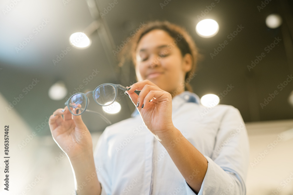 Hands of young contemporary mixed-race female holding pair of new eyeglasses Hands of young contemporary mixed-race female holding pair of new eyeglasses