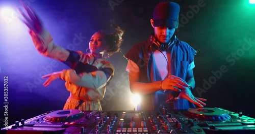 A dj couple is performing together in a nightclub, dancing at mixer controller, rocking the party up - nightlife concept 4k footage photo