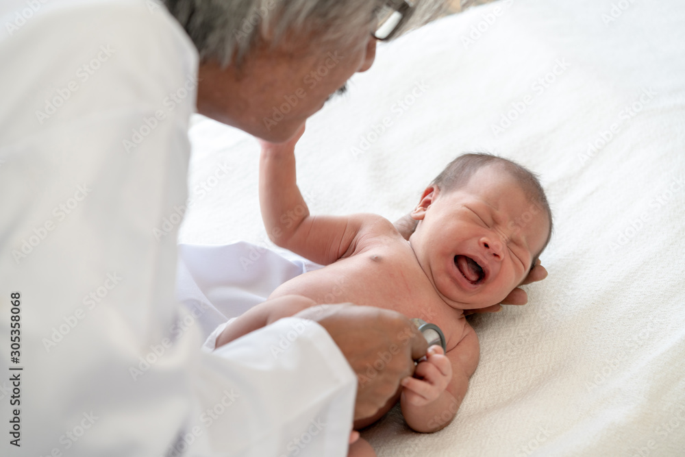Crying asian newborn baby girl check up examines by pediatrician doctor. Happy male doctor hand using stethoscope examining little cute baby infant heart and lung in clinic. Baby health care concept. Crying asian newborn baby girl check up examines by pediatrician doctor. Happy male doctor hand using stethoscope examining little cute baby infant heart and lung in clinic. Baby health care concept.