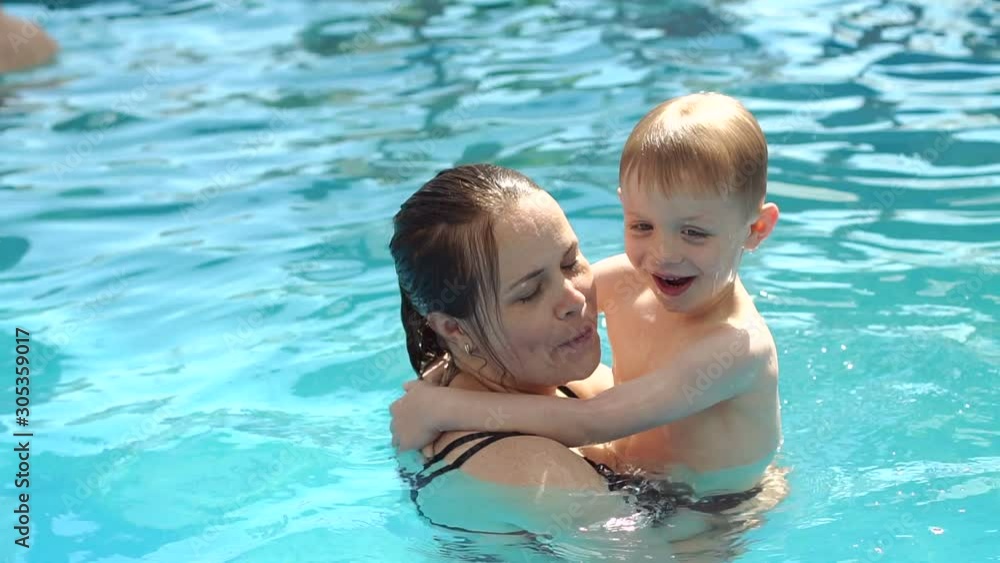 Portrait of a happy mother hugging her son while swimming in the pool on vacation at the hotel. Mom and baby swim in the pool and enjoy the vacation. Slow motion. Portrait of a happy mother hugging her son while swimming in the pool on vacation at the hotel. Mom and baby swim in the pool and enjoy the vacation. Slow motion.