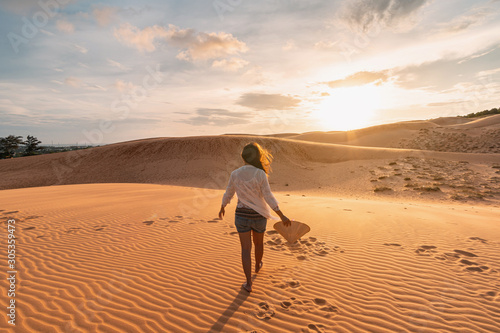 Young woman traveler looking sunset at red sand dunes in Vietnam, Travel lifestyle concept photo