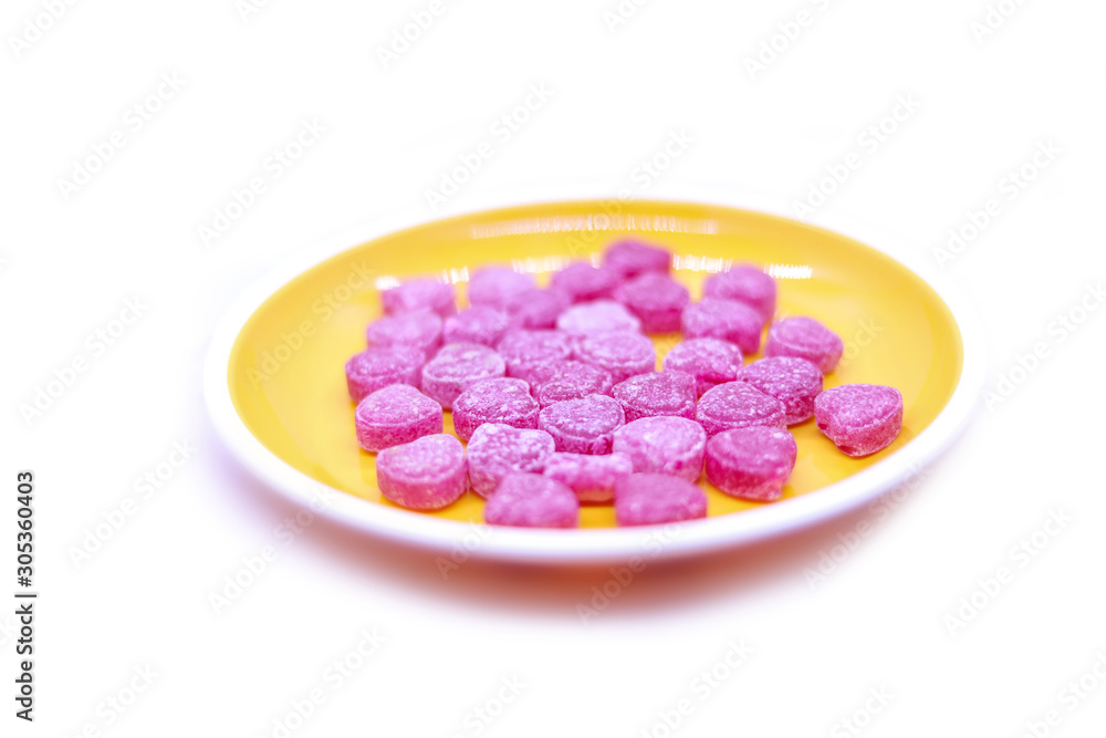 Bright colored candy sweets in a yellow plate on a white background top view Bright colored candy sweets in a yellow plate on a white background top view