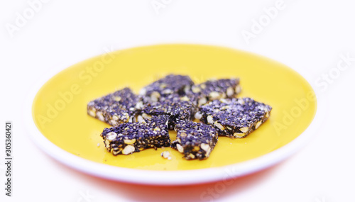 Indian Traditional Sweet Peanut Barfi, Ellu Mittai in a yellow plate on a white background top view photo