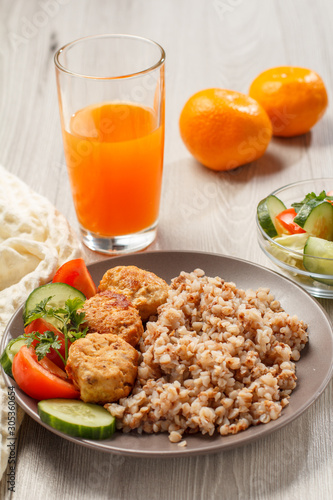 Plate with buckwheat, fried meat cutlets and pieces of fresh cucumber and tomato