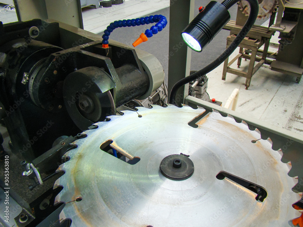 Machine for automatic sharpening of circular saws. Backlight from the lamp. Round sharp disk. Mechanisms of equipment.