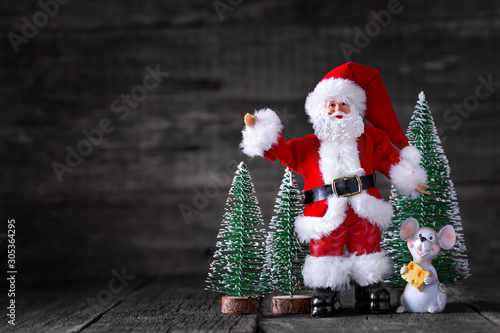 Toy of Santa Claus and mouse on wooden rustic background with New year trees