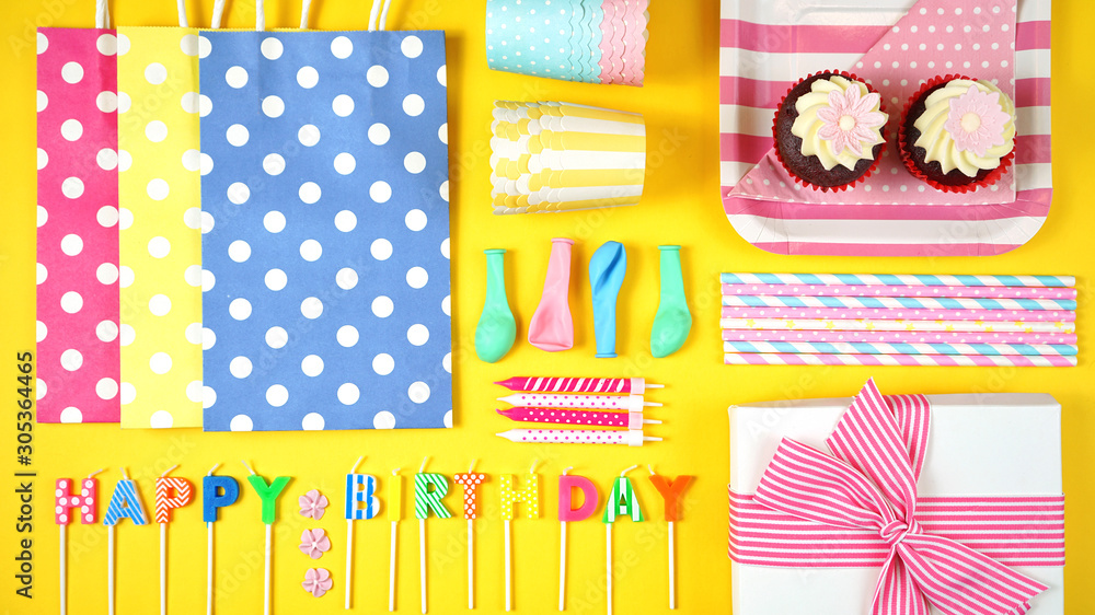 Obraz premium Colorful birthday party flat lay with party food, balloons, decorations and gifts on yellow background.